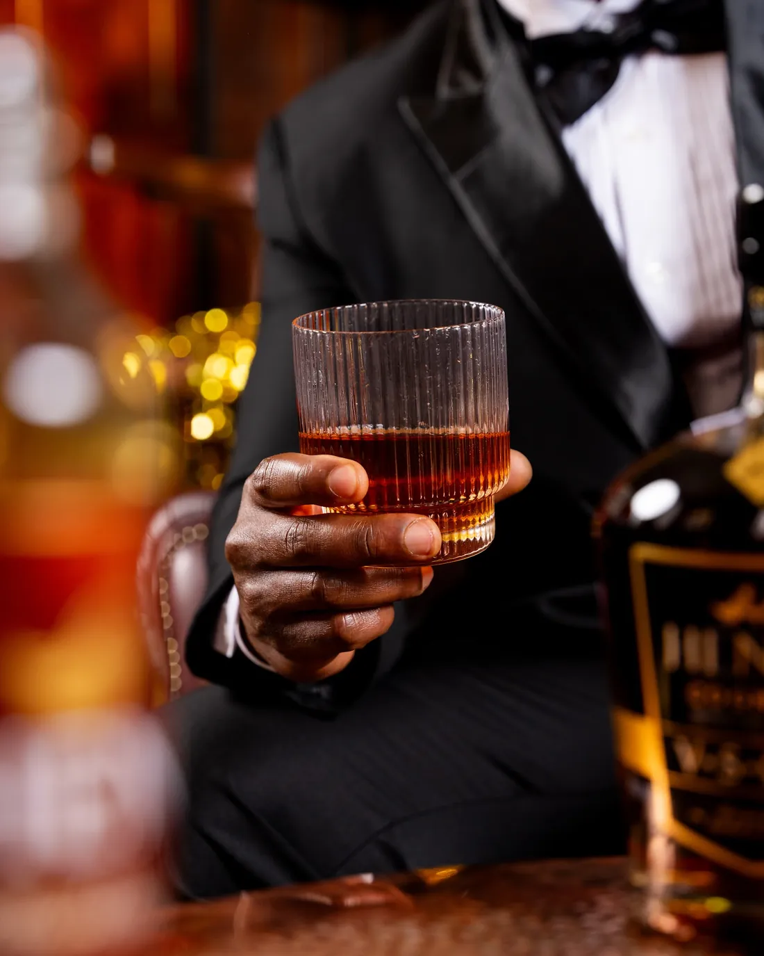 A glass of Henri cognac held against a tuxedo