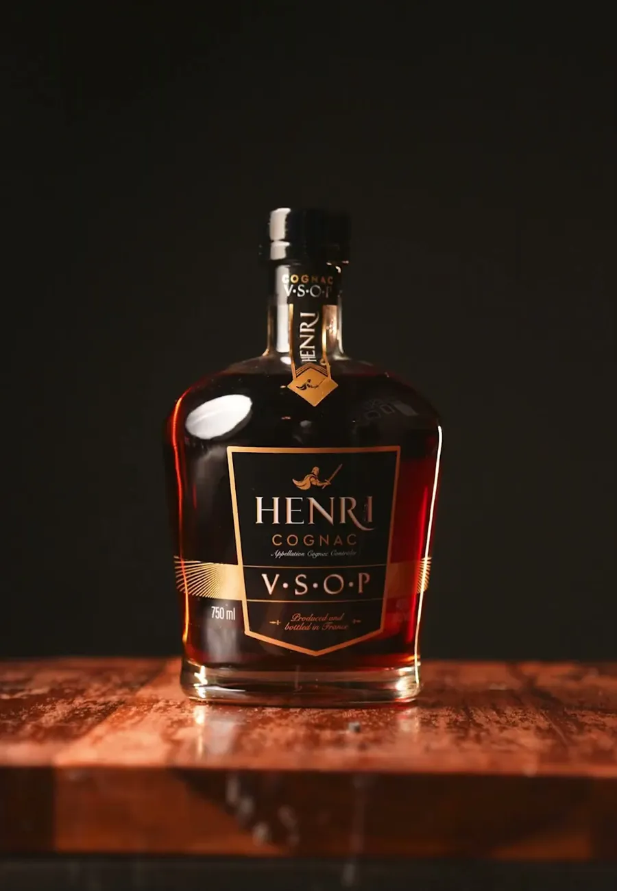A bottle of Henri V.S.O.P cognac on a polished wooden bar counter
